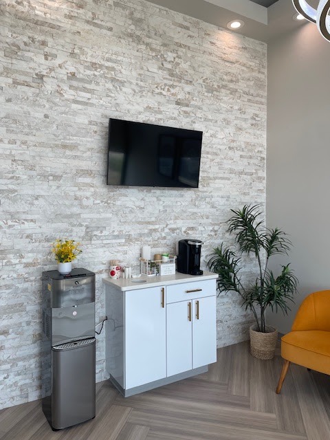 Coffee station and water dispenser beneath a TV on a stone accent wall