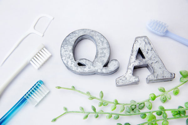 The letters Q and A surrounded by toothbrushes and a floss pick